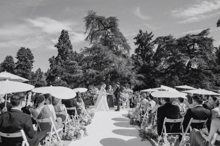 Black and white image of a wedding ceremony with guests seated under umbrellas at Schlosshotel Kronberg.